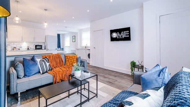 Un appartement moderne comprenant un espace de vie, une kitchenette et une pancarte sur laquelle on peut lire « ME STAYS ».