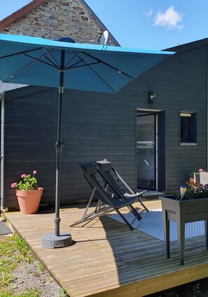 A wooden deck with a blue umbrella, a lounge chair, and a potted plant. - Charming studio with terrace (Ducey-Les Chéris)