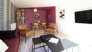 Ein Wohnzimmer mit einer Couch, Sesseln, einem Couchtisch und einem Essbereich mit Stühlen und einem Tisch.