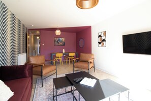 A living room with a sofa, armchairs, a coffee table, and a dining area with chairs and a table.