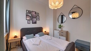A hotel room with a bed, bedside tables, a dresser, a mirror, and wall art. - RentPlanet - Apartament Sikorskiego (Szklarska Poręba)