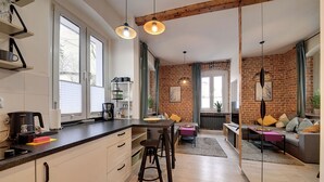 A modern kitchen with a central island, bar stools, and a dining area with a sofa and a coffee table. - RentPlanet - Apartament Sikorskiego (Szklarska Poręba)