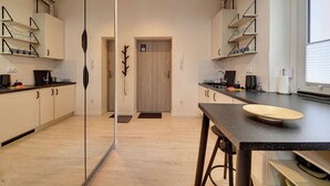 A modern kitchen with a central island, wooden cabinets, and built-in shelves. - RentPlanet - Apartament Sikorskiego (Szklarska Poręba)