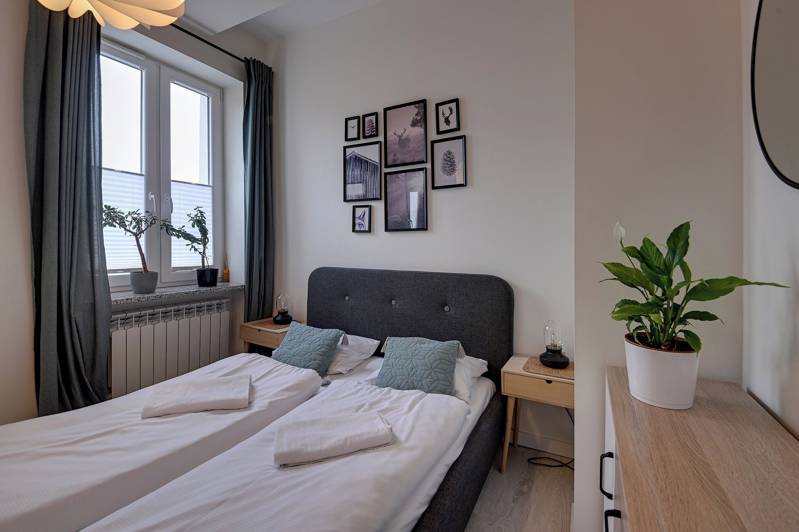 Un lit double avec du linge de lit blanc, une tête de lit grise et une table de chevet avec une lampe.