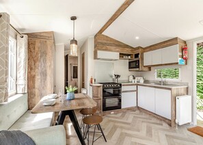 Cocina compacta con una isla central, electrodomésticos integrados y ventana con vistas a la vegetación.