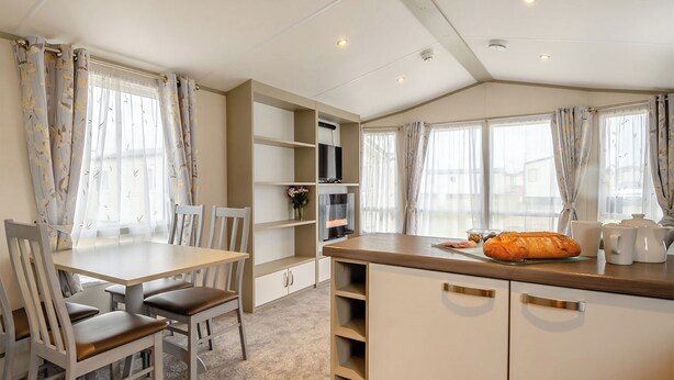 Een kleine keuken met een eethoek, met een tafel, stoelen en een aanrecht met keukengerei.