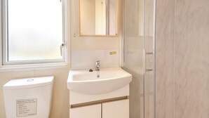 Een badkamer met toilet, wastafel, spiegel en douche.