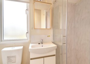 Een badkamer met toilet, wastafel, spiegel en douche.