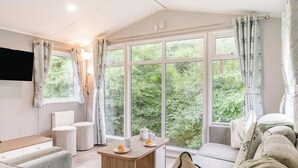 Ein gemütliches Zimmer mit einer Couch, einem kleinen Tisch mit Teekanne und Teller sowie einem Fenster mit Vorhängen.