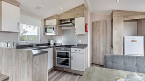 A compact kitchen with a microwave, stove, oven, and a small refrigerator. - Silver Caravan with ensuite P (Great Yarmouth)