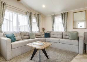 Ein Wohnzimmer mit einem Ecksofa, einem Holztisch und einem großen Spiegel an der Wand.