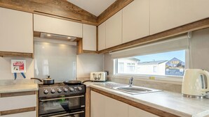Una cucina con piano cottura, forno, lavello e finestra vista su una casa.