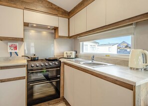 Eine Küche mit Herd, Backofen, Spüle und Fenster mit Blick auf ein Haus.