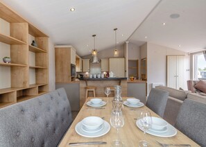 A modern kitchen with wooden cabinets, a central island, and pendant lighting. - Deluxe Lodge with parking, ensuite & decking (Great Yarmouth)