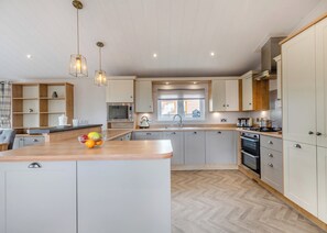 Een moderne keuken met een centraal eiland, houten kasten, een magnetron en een waterkoker.