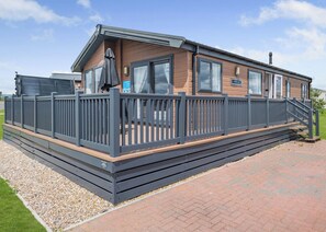 Een stacaravan met een terras, een overdekt buitengebied en een bord waarop 'Porland' staat.