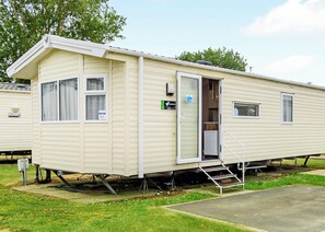A single-story mobile home with a door, windows, and a small porch area. - Silver Premium Caravan with parking (Great Yarmouth)