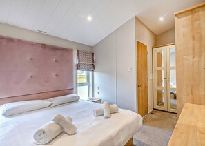 Een slaapkamer met een groot bed, een houten kledingkast, een raam met uitzicht en een deur naar een andere kamer.
