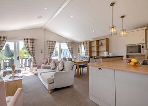 A cozy living area with a sofa, dining table, and kitchen counter. - Deluxe Lodge with parking, ensuite & decking P (Great Yarmouth)