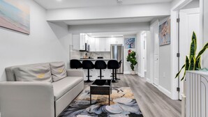 Ein modernes Wohnzimmer mit einer Couch, einem Couchtisch und einer Küche im Hintergrund.