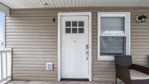 A house with a white front door, a window with a white frame, and a wicker chair on the porch. - 1BR, Free Parking, Steps to the Boardwalk (Seaside Heights)