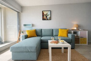 Una sala moderna con un sofá modular, una mesa de centro con aperitivos, una lámpara y un cuadro en la pared.