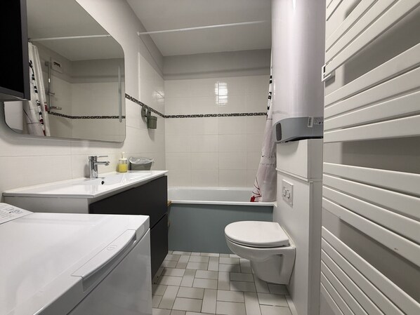 A bathroom with a white sink, mirror, toilet, and bathtub. - Apartment facing the sea – balcony, 4 guests (Les Sables-d´Olonne)