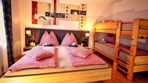 Una cama con ropa de cama cuadriculada, cabecera, lámparas de noche y una escalera de madera.