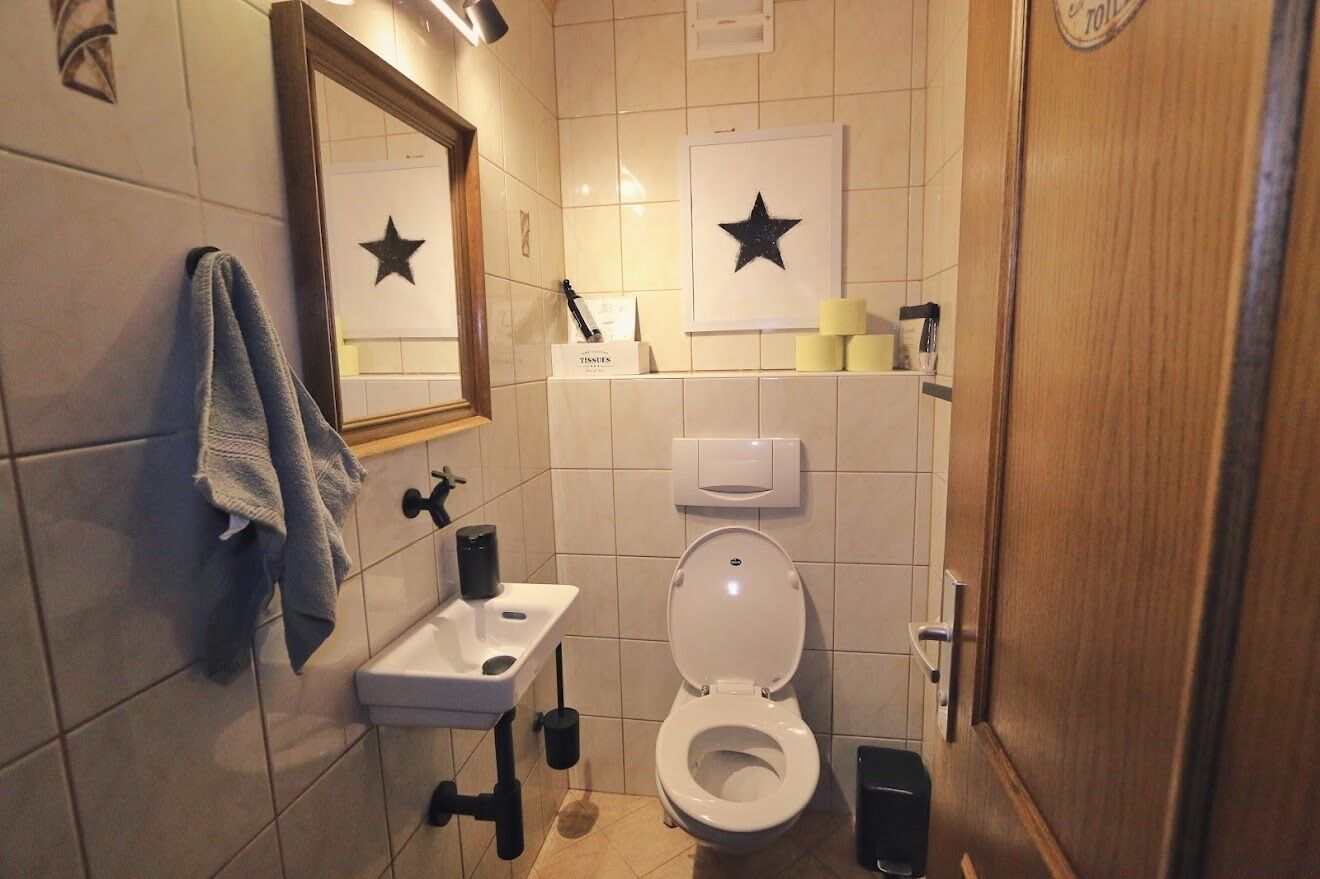 Une salle de bain équipée de toilettes, d’un lavabo, d’un miroir et d’un porte-serviettes.