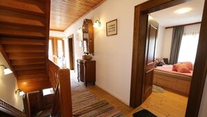 Una escalera de madera que conduce a un dormitorio con una cama, un aparador y un espejo.