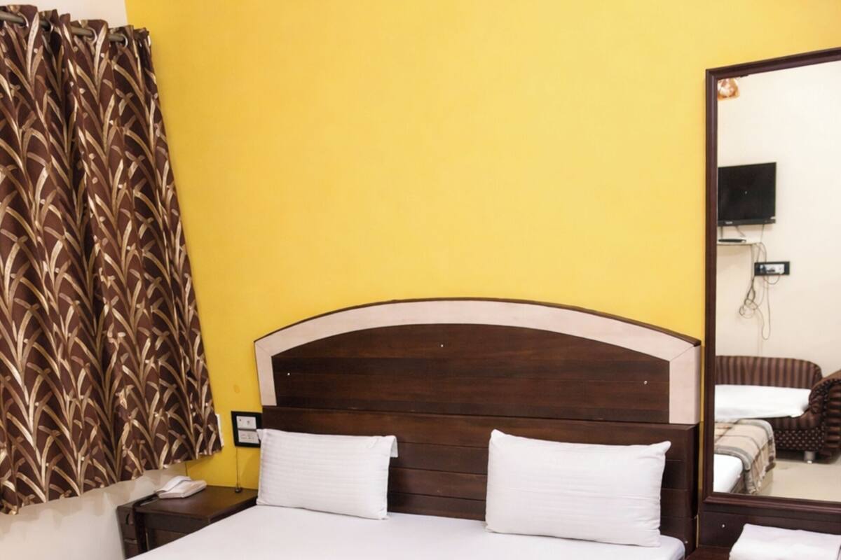 A bed with a wooden headboard, white bedding, and a plaid blanket.