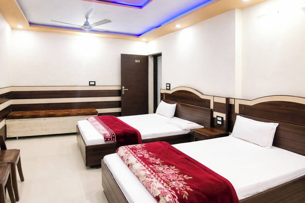 A hotel room with two beds, a ceiling fan, and a door.