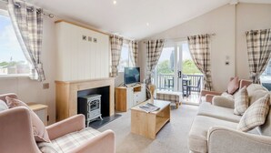 A cozy living room with a fireplace, sofa, and television. - Deluxe 2, Slps 4, parking, ensuite, decking, HT (Burgh Castle, Great Yarmouth)