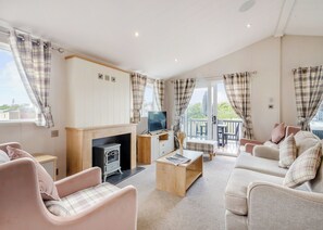 A cozy living room with a fireplace, sofa, and television. - Deluxe 2, Slps 4, parking, ensuite, decking, HT (Burgh Castle, Great Yarmouth)