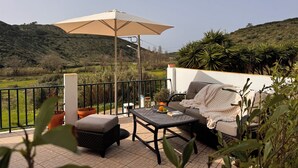 Un patio con mobiliario exterior, una mesa y una sombrilla.