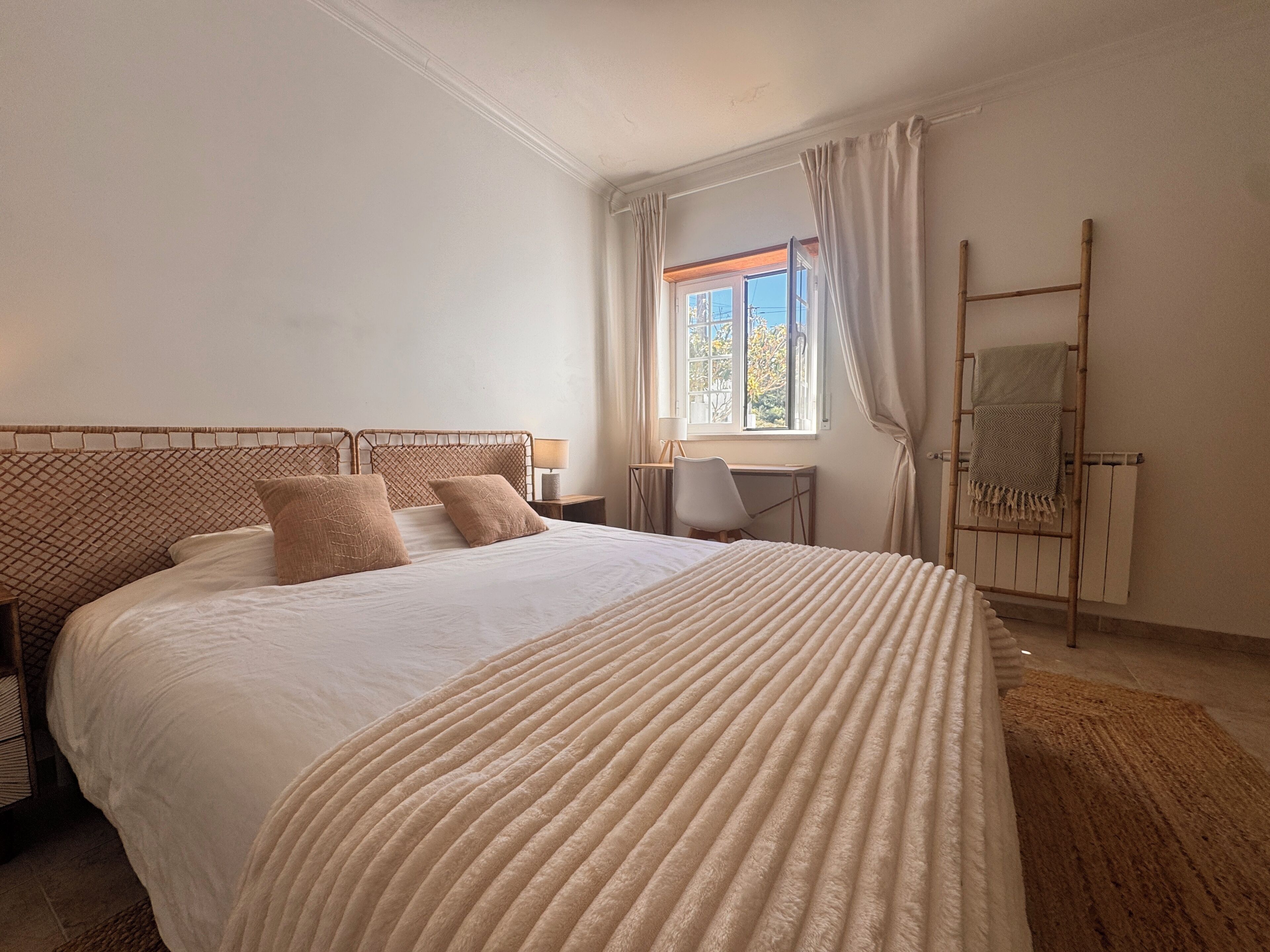 Un dormitorio con una cama grande, un escritorio y una ventana con cortinas.
