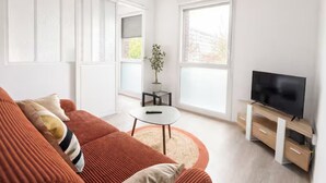 Un salon moderne avec un canapé, un téléviseur et une petite table.