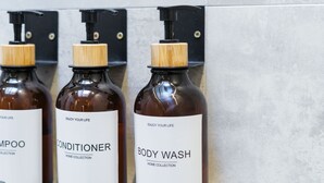 Three bottles of shampoo, conditioner, and body wash with pump dispensers, mounted on a wall. - Relaxing 5BR Apartment Close to Downtown (Ghent)