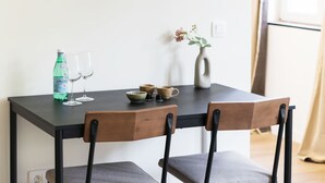 A dining table with chairs, a bottle of water, two glasses, and a vase with flowers. - Relaxing 5BR Apartment Close to Downtown (Ghent)