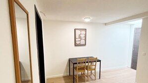 A hallway with a dining table and chairs, a framed picture on the wall, and a door at the end. - Relaxing 5BR Apartment Close to Downtown (Ghent)