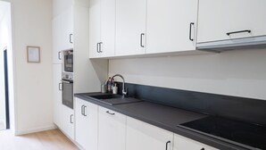 A modern kitchen with white cabinetry, a black countertop, and a stainless steel sink. - Relaxing 5BR Apartment Close to Downtown (Ghent)