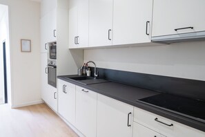 Eine moderne Küche mit weißen Schränken, einer schwarzen Arbeitsplatte und einem Edelstahlspülbecken.