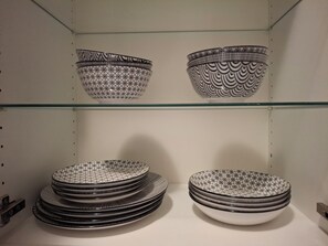 Eine Auswahl an Schüsseln und Tellern mit geometrischen Mustern, präsentiert auf Regalböden in einem Geschäft.
