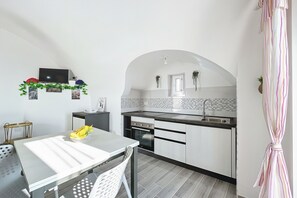 A modern kitchen with white cabinets, a built-in oven, and a dining area with a table and chairs.
