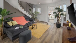Ein modernes Wohnzimmer mit einer Couch, einem Couchtisch und Topfpflanzen.