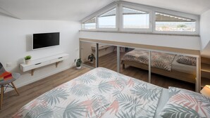 Ein Schlafzimmer mit einem Bett, einem Fernseher, einem Schreibtisch und einem Fenster.