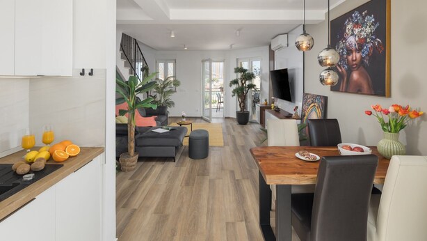 Eine moderne Küche mit Essbereich, einer Treppe und einem Wohnzimmer mit großem Fenster.