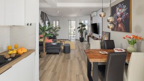 Une cuisine moderne avec un coin repas, un escalier et un salon doté d’une grande fenêtre.