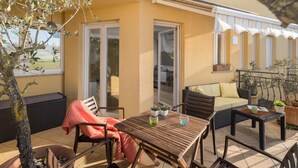 Eine Terrasse im Freien mit Holztisch, Stühlen, einer Couch und einem kleinen Feuerkorb.