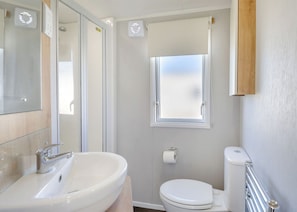 A bathroom with a sink, toilet, and window. - Bronze 2 Bedroom Caravan, Sleeps 6 (Walton-on-the-Naze)